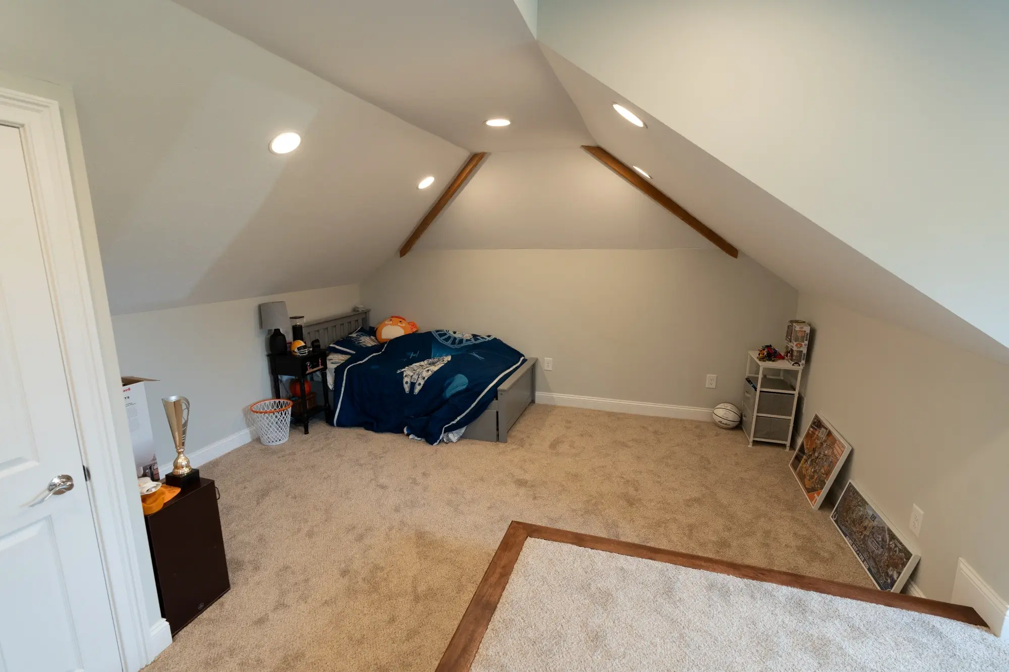 Converted attic bedroom space with sloped ceiling and built-in lighting by AY Remodeling and Restoration