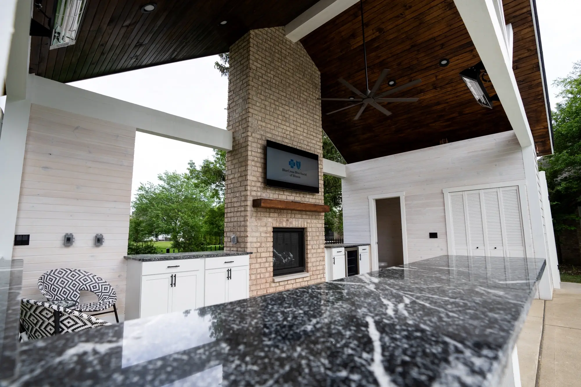 Luxury outdoor kitchen and fireplace under completed pool house pavilion addition by AY Remodeling & Restoration