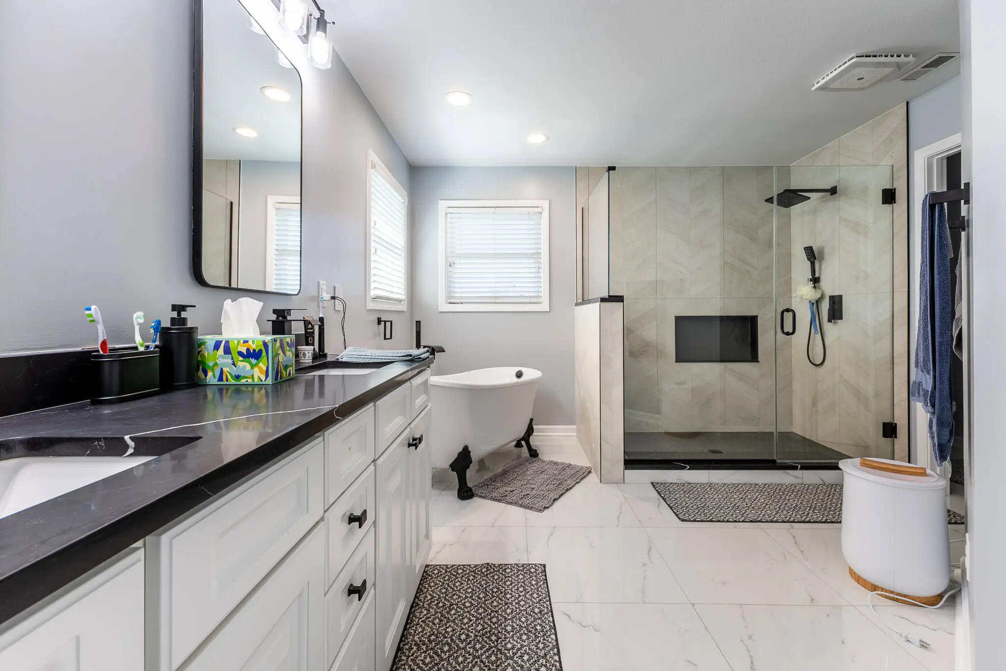 Contemporary bathroom renovation with double vanity, matte black fixtures, freestanding clawfoot tub, and large walk-in shower with glass enclosure.