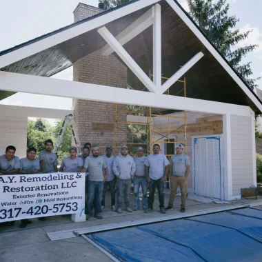 AY Remodeling & Restoration team posing in front of in-progress custom pool house addition